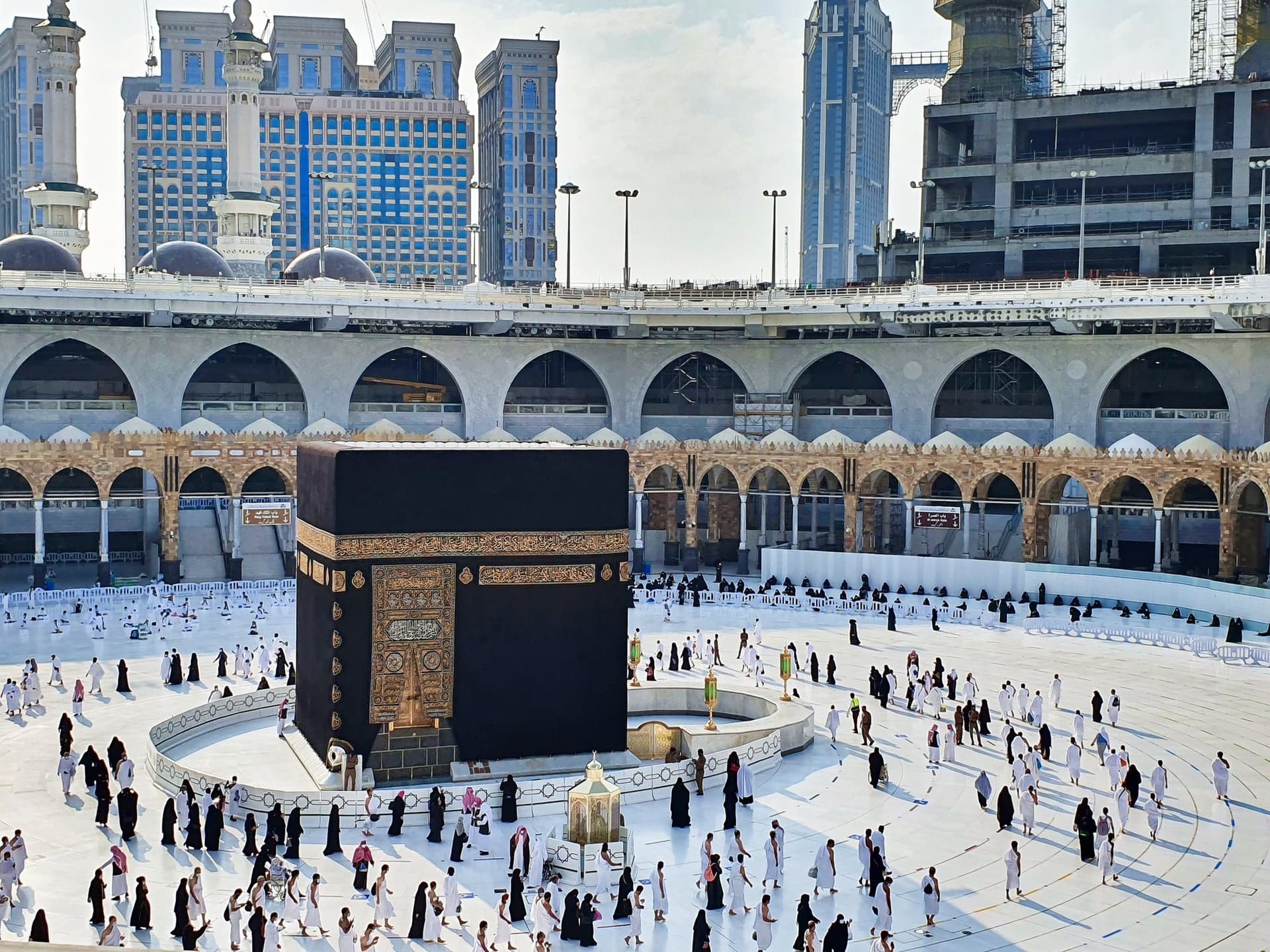 Gündüz vakti Mescid-i Haram'ın beyaz mermer metafında Kâbe ve tavaf eden ziyaretçiler
