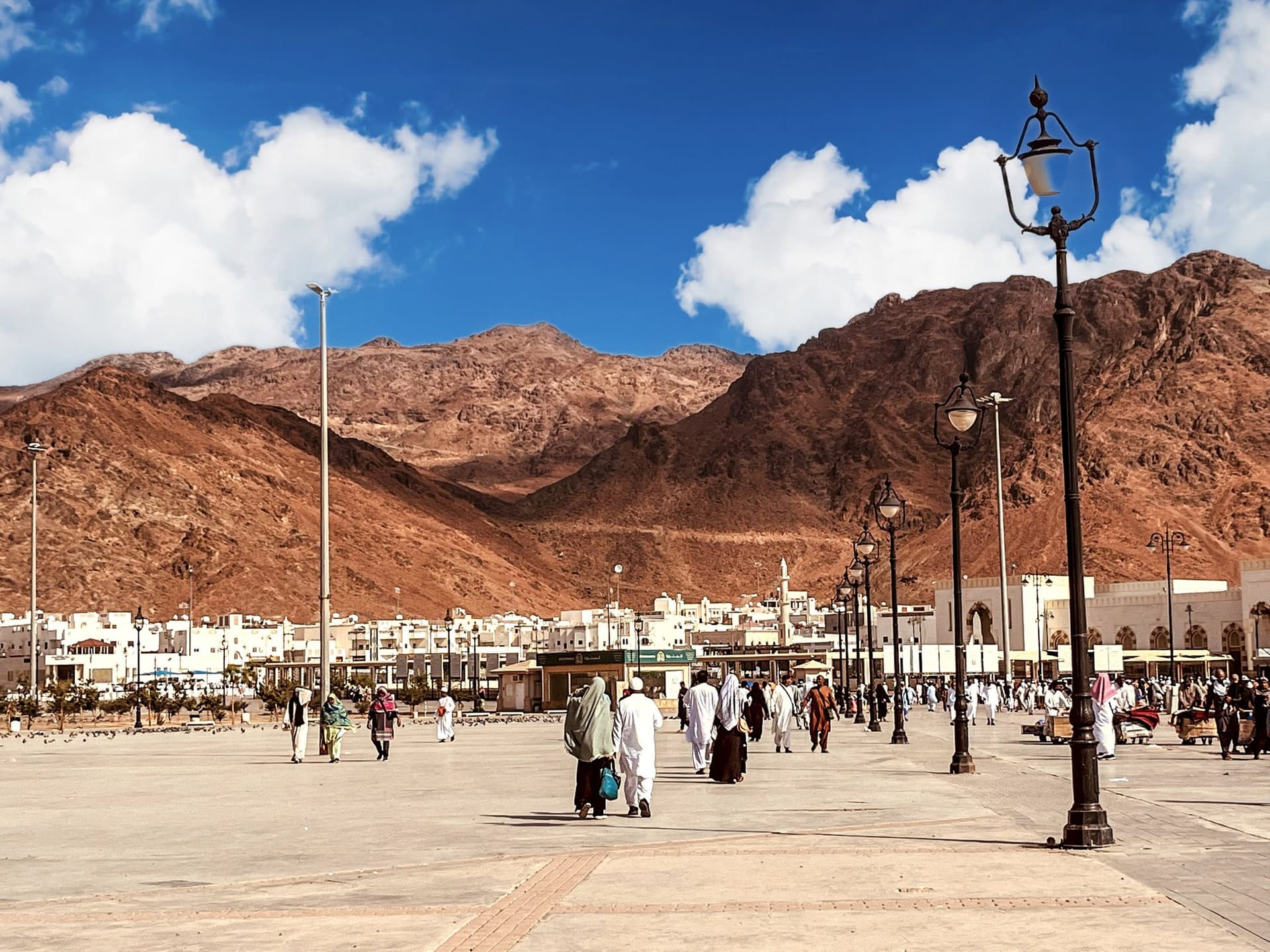 Mavi gökyüzü altında kızıl tonlu Uhud Dağı ve eteğindeki Seyyidü'ş-Şüheda meydanı, Medine