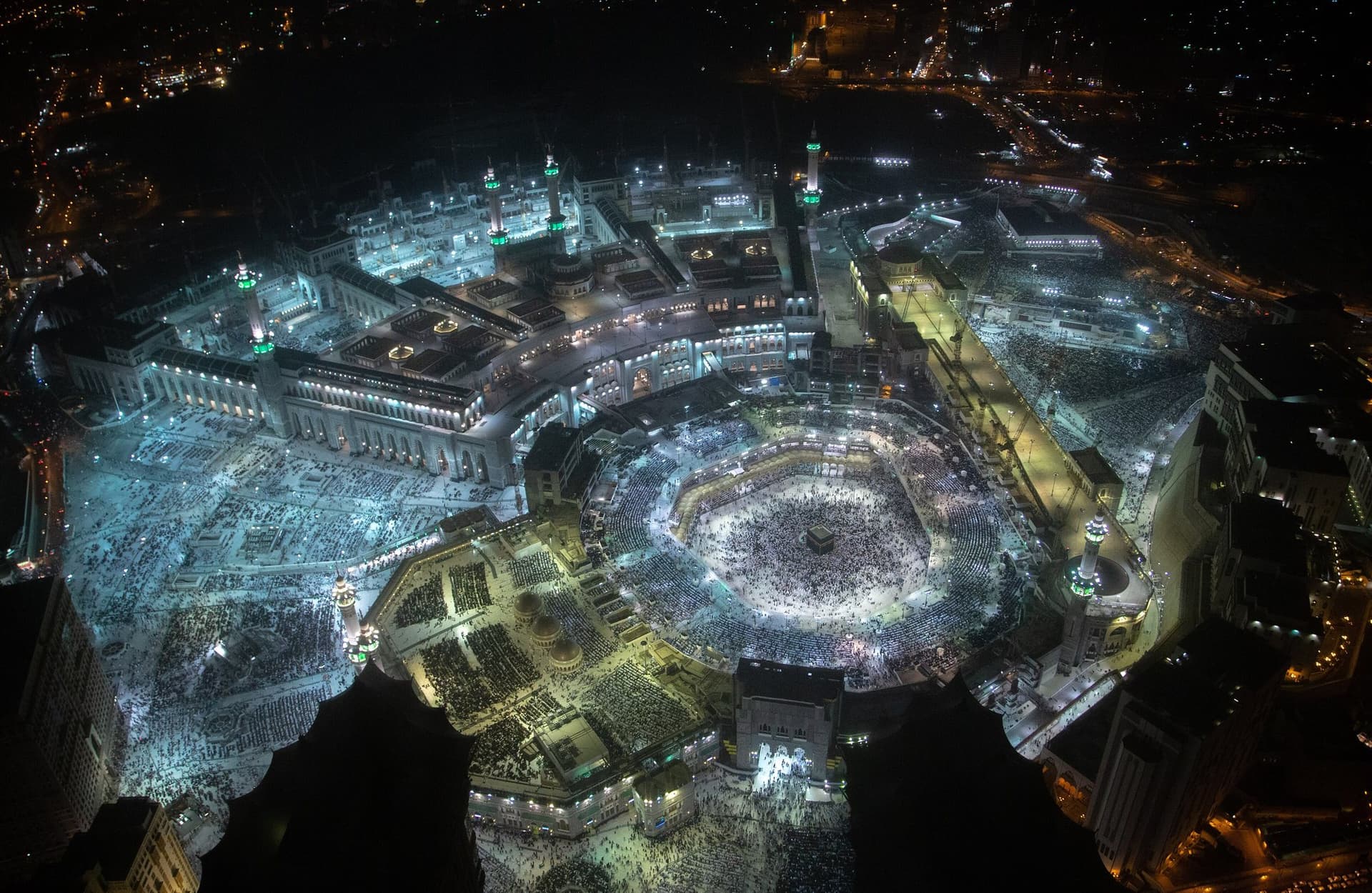 Gece ışıklarıyla aydınlanan Mescid-i Haram, ortada Kâbe-i Muazzama ve avluyu dolduran cemaat, yüksekten görünüm